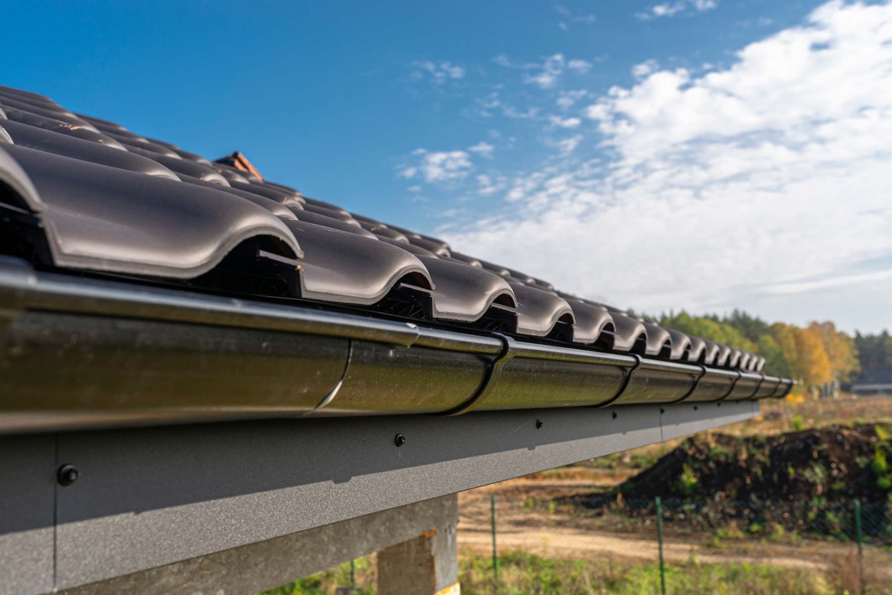 a-metal-black-gutter-on-a-roof-covered-with-ceram-2023-11-27-05-16-19-utc a-metal-black-gutter-on-a-roof-covered-with-ceram